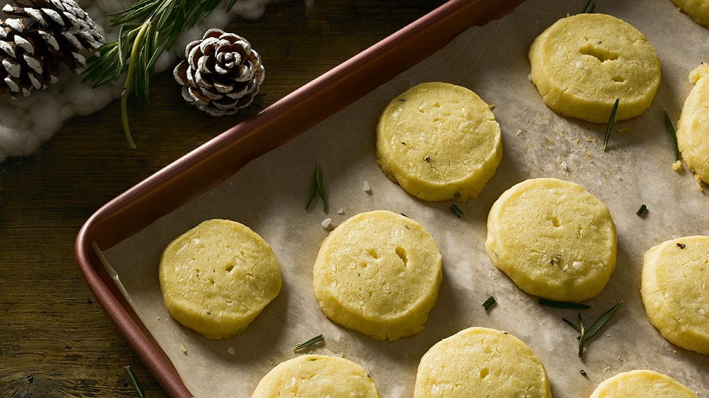 Round rosemary and cheddar shortbread cookies on silver pan.