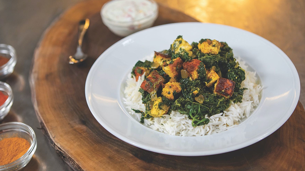 Saag Paneer on bed of rice in white round bowl.