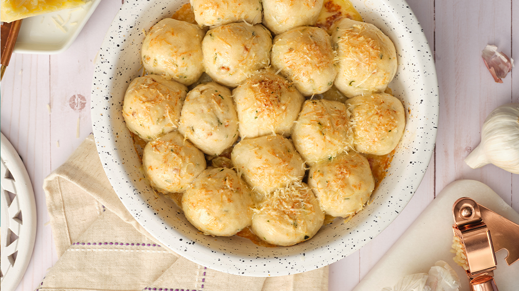 Round cheese bread bombs in white bowl.